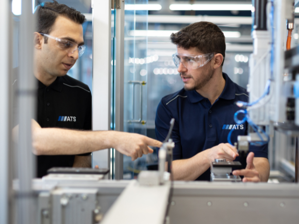 Two individuals working on automation equipment