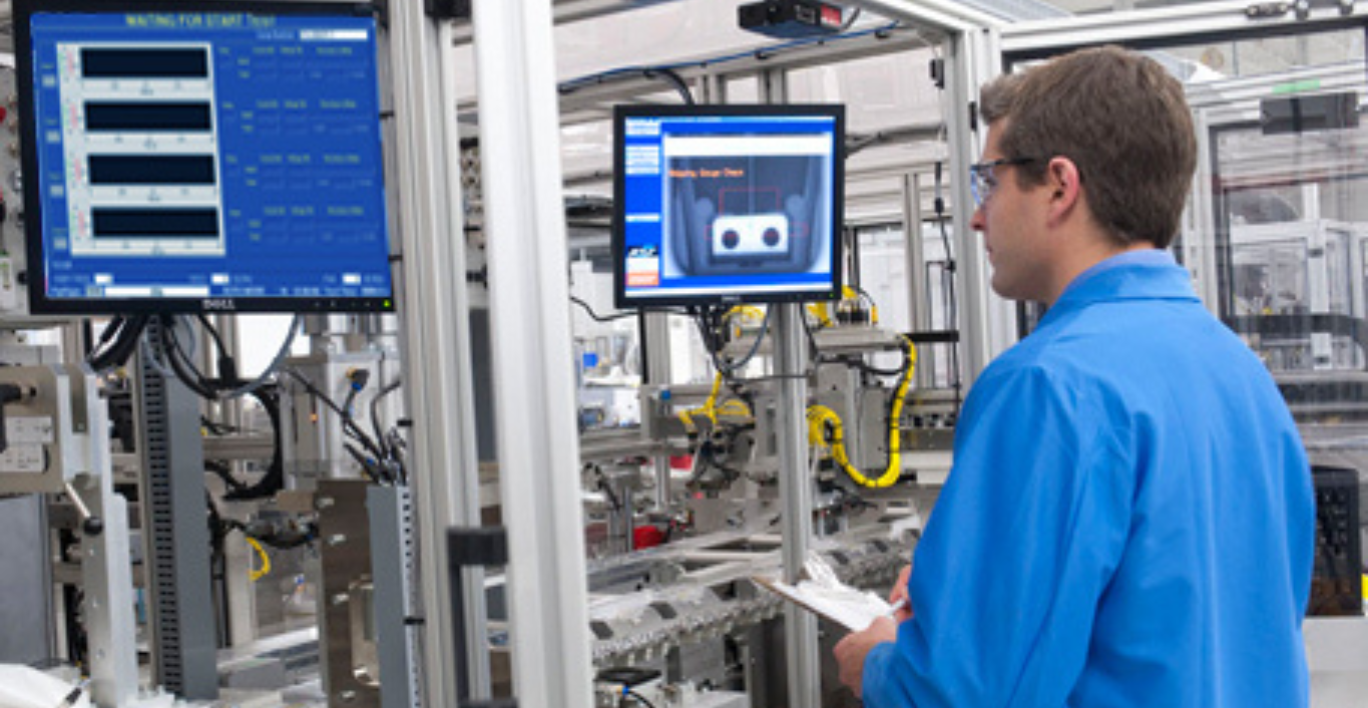 Man standing near production equipment reviewing information on a screen